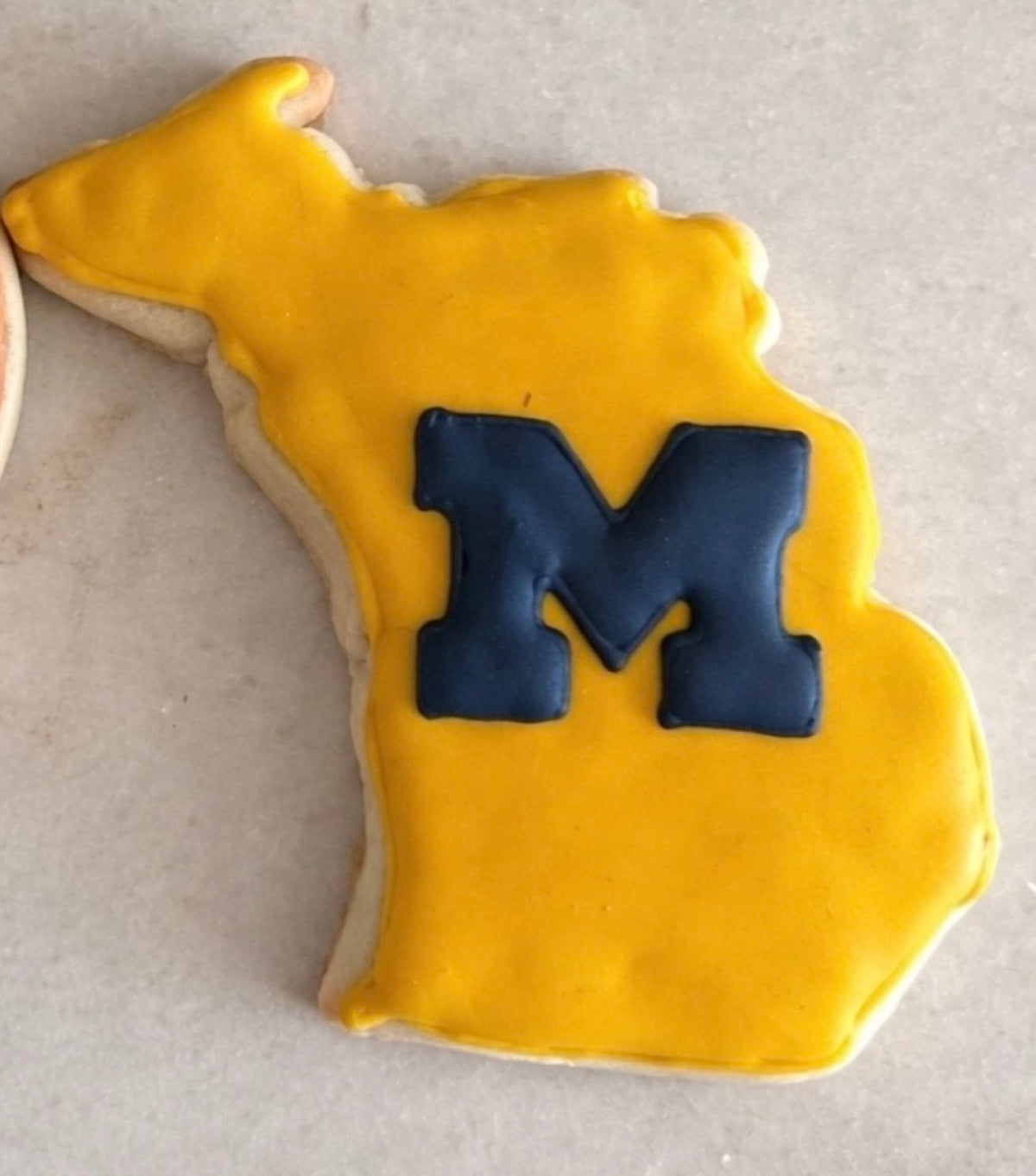 Michigan-shaped sugar cookie hand-decorated with a navy Block M